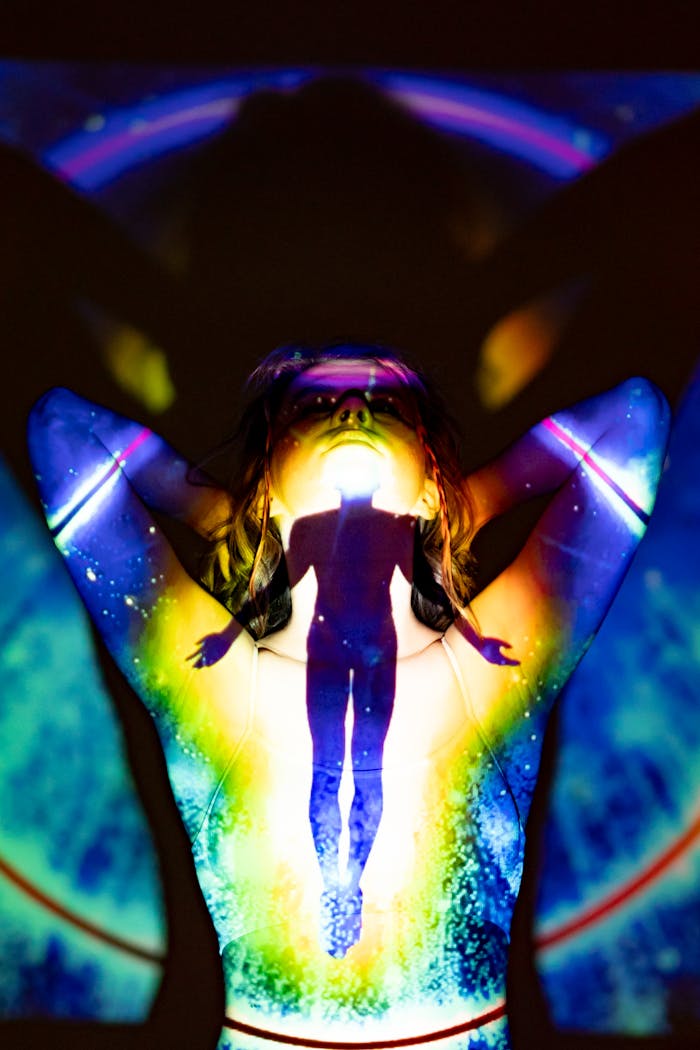 A silhouette emerges through colorful projections, evoking spirituality and energy.